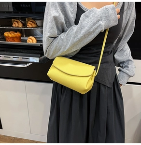 Detail of a yellow pebble grain crossbody bag shown on a model in a casual setting