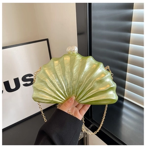 Gros plan d'une pochette coquillage vert clair nacré avec fermoir perle et chaîne dorée