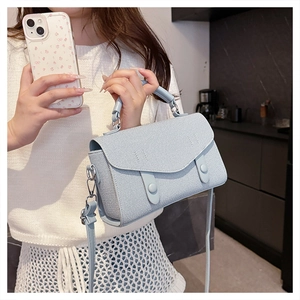 Close-up of light blue messenger bag with textured fabric and adjustable leather strap