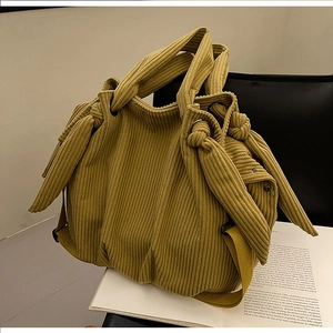Close-up of mustard yellow corduroy tote bag featuring unique knot handle detail