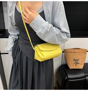 Minimalist yellow crossbody bag in pebbled leather shown on a model with grey cardigan