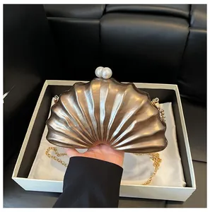 Détail d'une pochette en résine en forme de coquille avec fermoir perle et chaîne dorée
