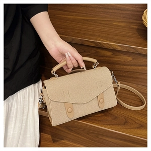 Close-up of beige woven texture handbag with leather handle on wooden stairs