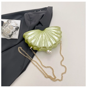 Détail d'une pochette en acrylique vert clair en forme de coquille avec fermoir perle
