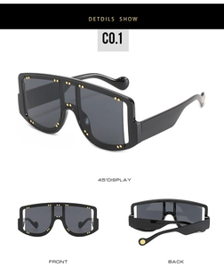 Detail of oversized square sunglasses with gold rivets and dark grey lenses in black frames