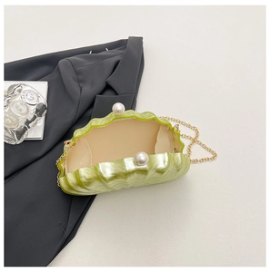 Détail d'un sac de soirée en forme de coquille verte avec fermoir perle et chaîne dorée