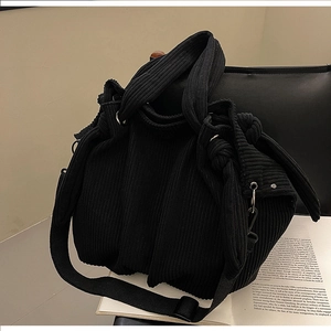 Close-up of black corduroy tote bag showing knotted handle and soft ribbed texture