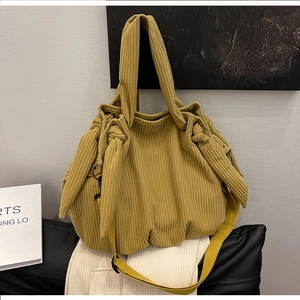 Detail of ginger corduroy tote bag with side knot and soft texture against a neutral wall
