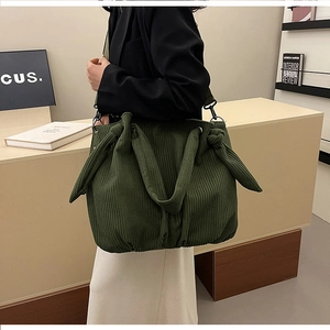 Detail of dark green corduroy shoulder bag featuring a unique knotted handle and strap