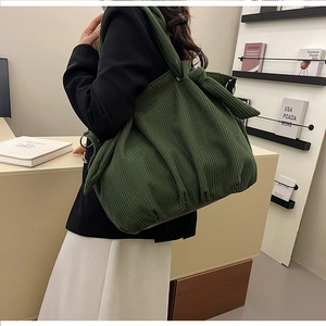 Detail of the oversized decorative knot on the deep green corduroy shoulder strap