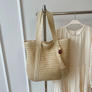 Summer straw tote bag with woven hollow design and beaded tassel for beach vacations