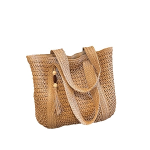 Handwoven straw tote bag with fringe detail and wide shoulder strap on white background
