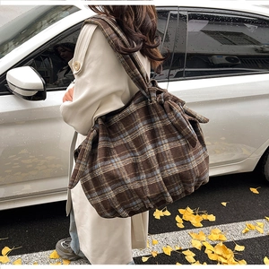Outdoor shot of a vintage brown plaid corduroy hobo bag on a person's shoulder