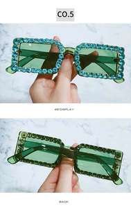 Detailed views of green square sunglasses with light blue rhinestones on marble background