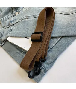 Detail of adjustable brown canvas strap with black buckle on denim background