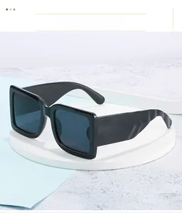 Detail of stylish oversized black square sunglasses displayed on a white round podium