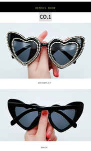 Detail view of heart-shaped sunglasses with sparkling white rhinestones and dark lenses