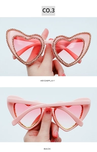 Detail view of heart-shaped pink sunglasses with rhinestone frames from 45 degree angle