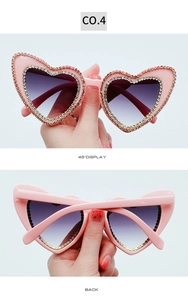 Detail view of pink heart-shaped rhinestone sunglasses with purple gradient lenses
