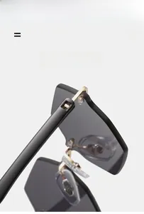 Detail of rimless sunglasses with grey lenses and gold metal hinges for lightweight design