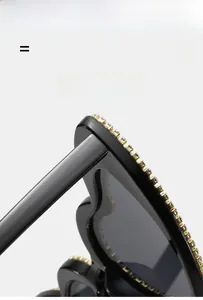 Macro shot of sparkling rhinestones on black heart-shaped sunglasses with golden metal trim