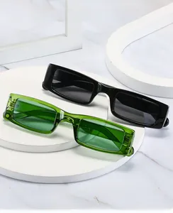 Close-up of narrow rectangular sunglasses in black and green on a marble background