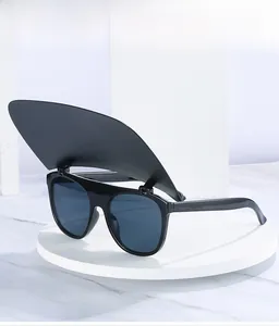 Detail shot of black flip-up sunglasses with protective sun visor on white stand