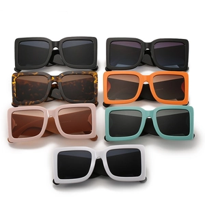 Flat lay of retro square sunglasses in black, orange, and white with thick frames
