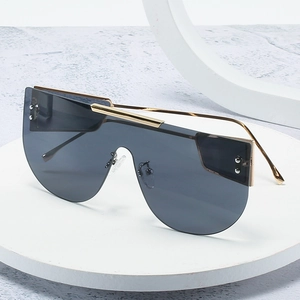 Chic oversized one-piece shield sunglasses with gold metal frame on a white display