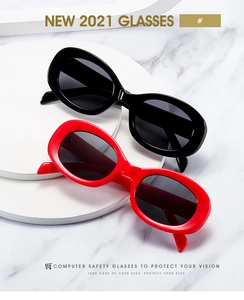 Detail of retro oval-frame sunglasses in black and red on a white marble platform