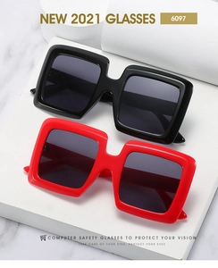 Close-up of black and red thick frame oversized square sunglasses on marble surface