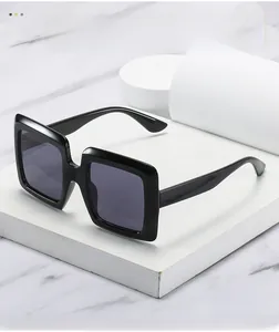 Detailed view of glossy black oversized square sunglasses on white marble display