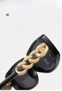 Detailed macro view of matte gold chain link decoration on black square sunglasses frame