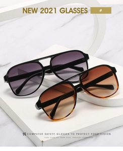 Detail of retro pilot sunglasses with black and tortoise frames on a white pedestal