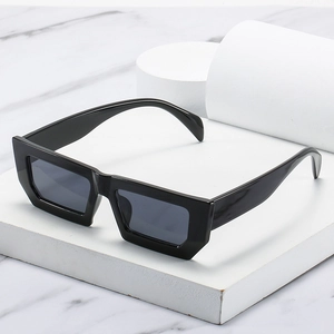 Retro black rectangular sunglasses with dark grey lenses on a marble display stand