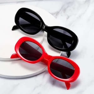 Retro oval sunglasses in black and red colors with thick polished frames on marble