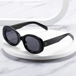 Classic oval black sunglasses with thick frames and dark lenses on a marble surface