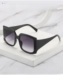 Gros plan sur des lunettes de soleil carrées noires avec verres dégradés violets sur socle