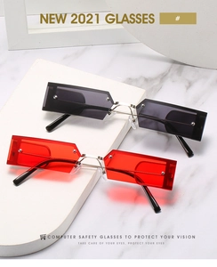 Detail of square rimless sunglasses with dark grey and red lenses and metal rivets