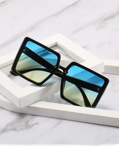 Detail of square oversized sunglasses with blue-yellow gradient lenses on marble base