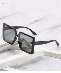 Detail view of black square sunglasses with gold stud accents on marble surface