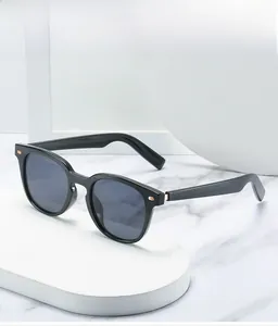 Détail de lunettes de soleil rondes noires avec accents dorés sur fond minimaliste