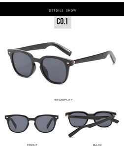 Détail de lunettes de soleil rondes noires avec rivets dorés et verres UV gris