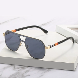 Trendy oversized pilot sunglasses in black and gold with iconic striped temples on a white stand