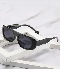 Détail de lunettes de soleil noires à monture épaisse sur un fond de marbre chic