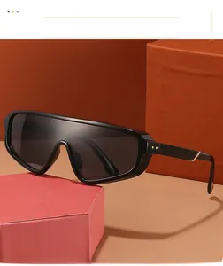 Detail of oversized black wrap sunglasses with gold temple accents on a geometric pedestal