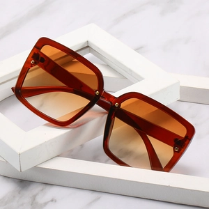 Lunettes de soleil rectangulaires rétro ambre avec rivets métalliques sur fond marbre