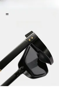 Detail of glossy black oversized sunglasses frame with decorative gold rivets on hinges