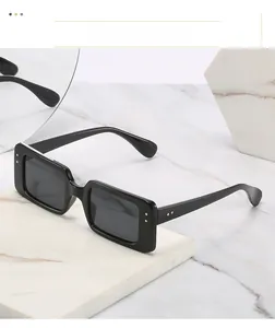 Close-up of retro square black sunglasses with silver rivet accents on marble surface