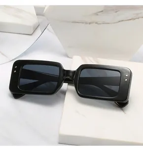 Detail of black rectangular sunglasses with grey lenses on white marble texture base